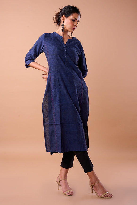 A graceful woman wearing a handwoven plain long kurta in a beautiful hue, adorned with intricate thread work on the neckline, cuffs, and hem. The kurta drapes elegantly, reflecting the timeless charm of traditional craftsmanship and modern style.